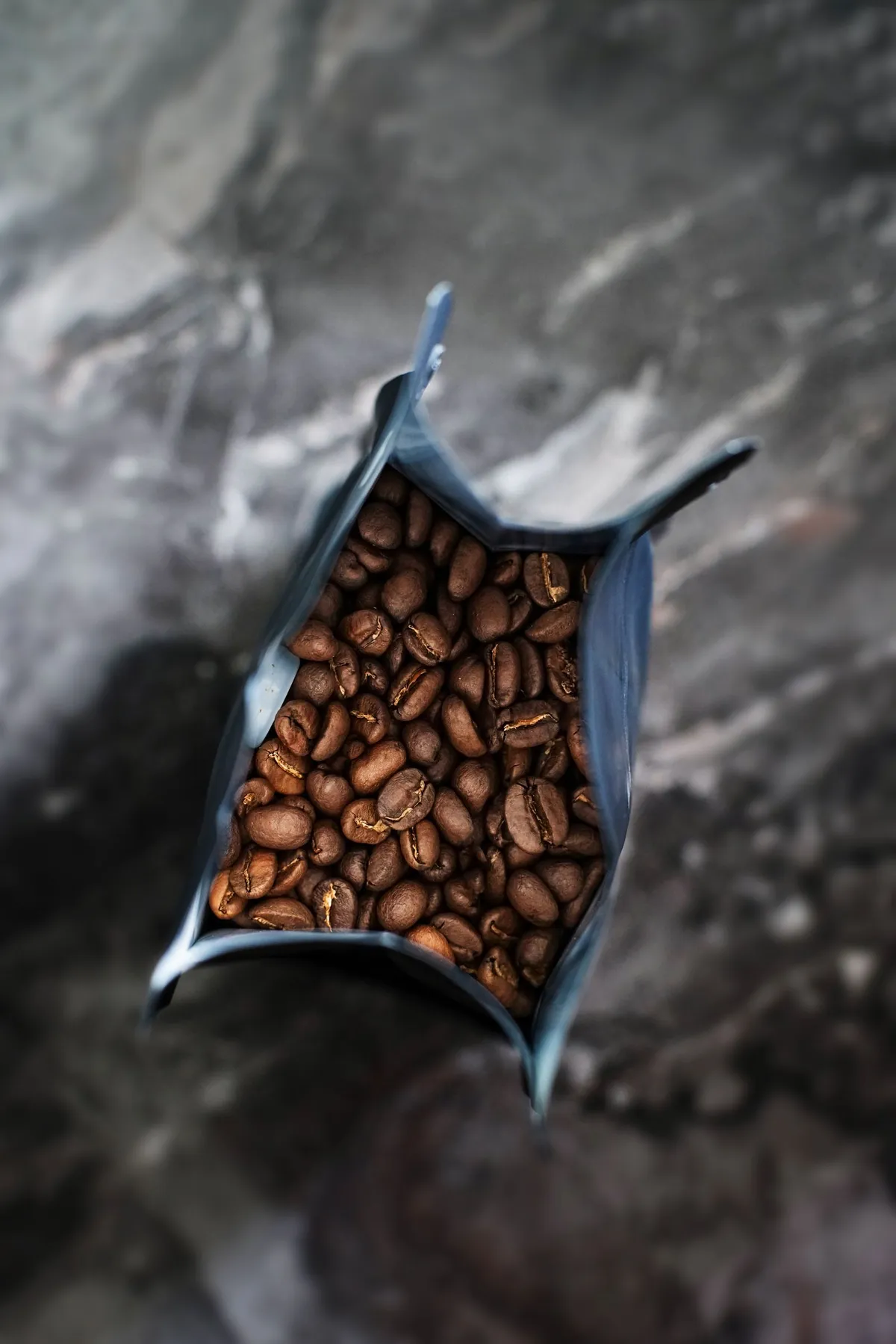 Vista cenital de granos de café tostados en un paquete abierto
