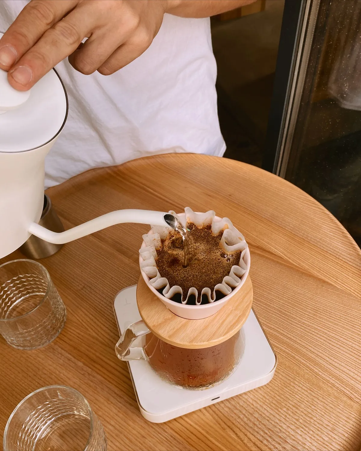 Mano vertiendo agua caliente en círculos sobre un filtro de café V60 con una jarra debajo