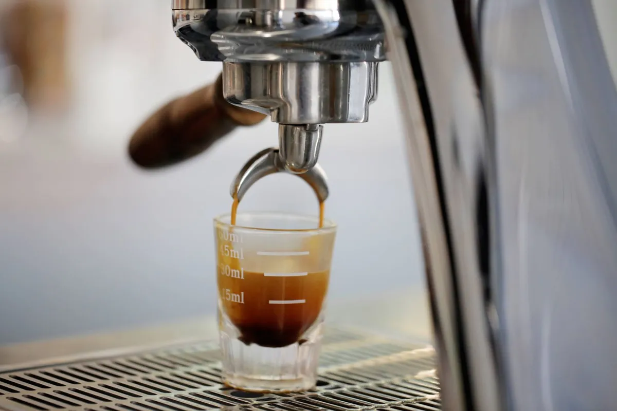 Extracción de un espresso desde la cafetera hacia una taza de cristal
