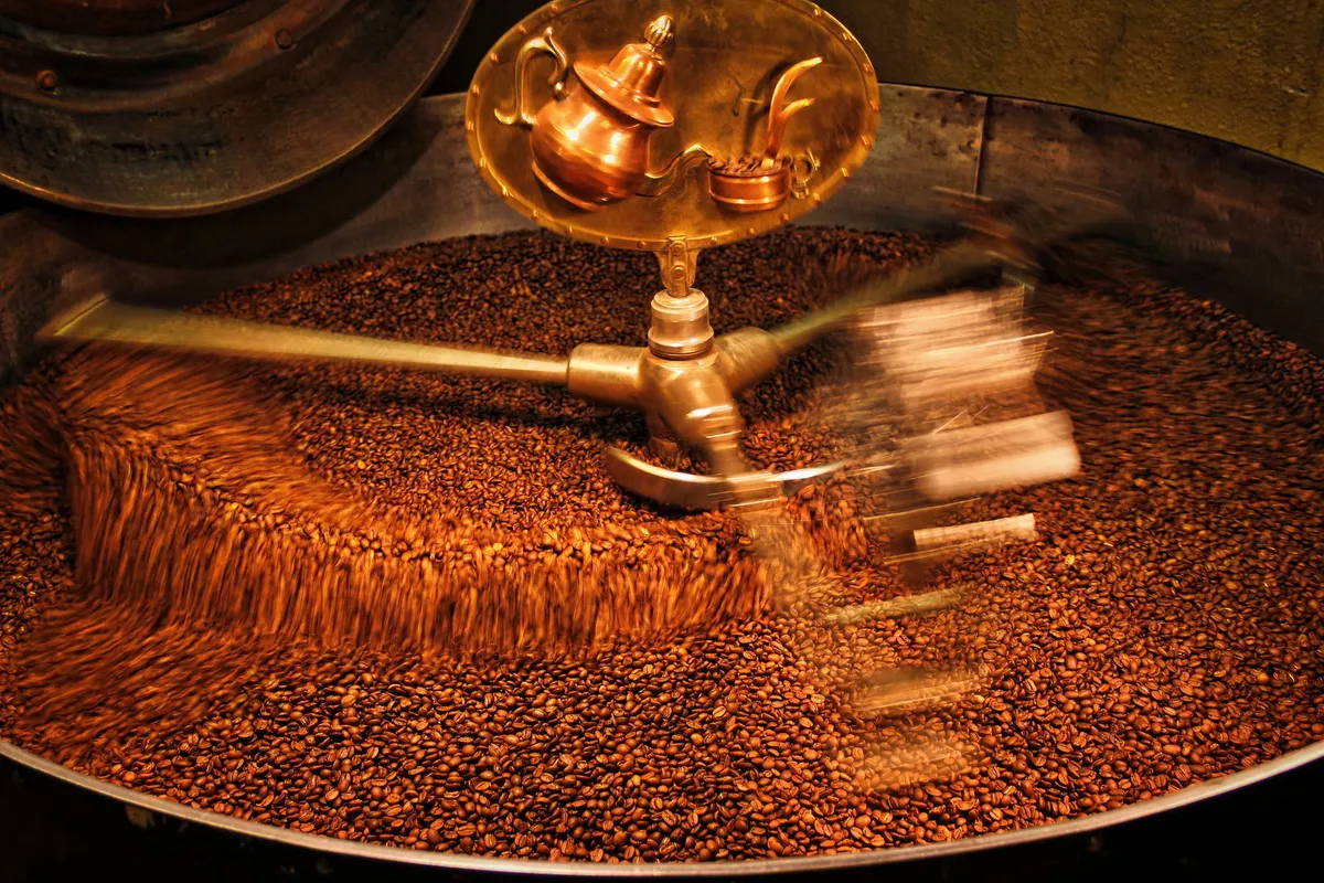 Granos de café tostándose en un tambor de tueste industrial