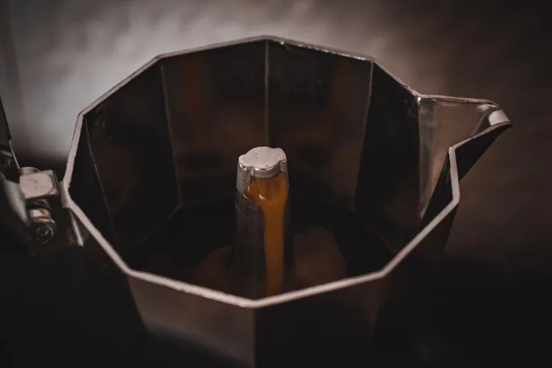 Primer plano del café brotando en una cafetera moka de acero