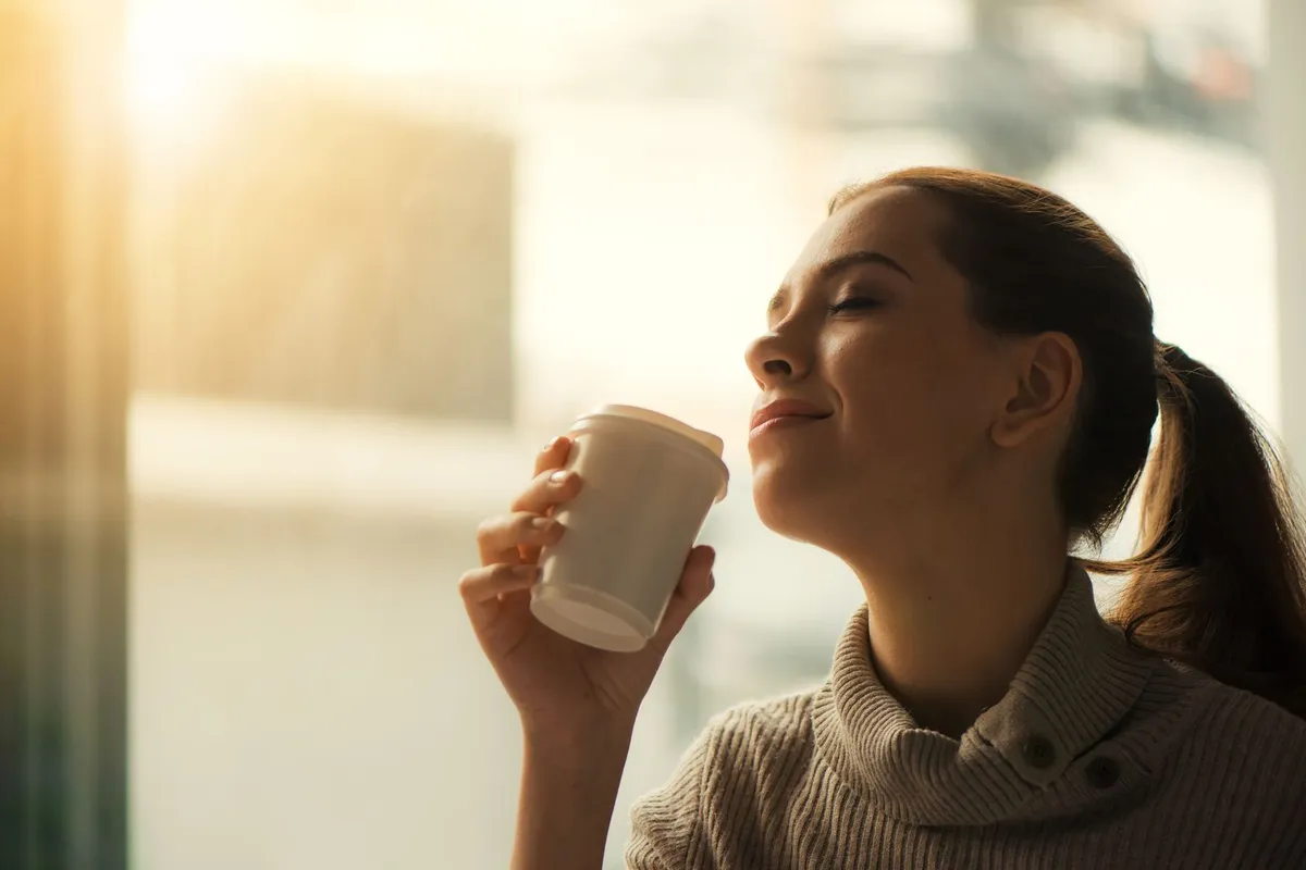Mujer disfrutando de su café de la mañana junto a la ventana