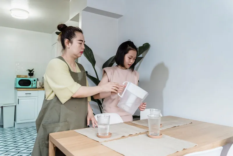 Jarra filtrante de agua sirviendo un vaso sobre una mesa de cocina