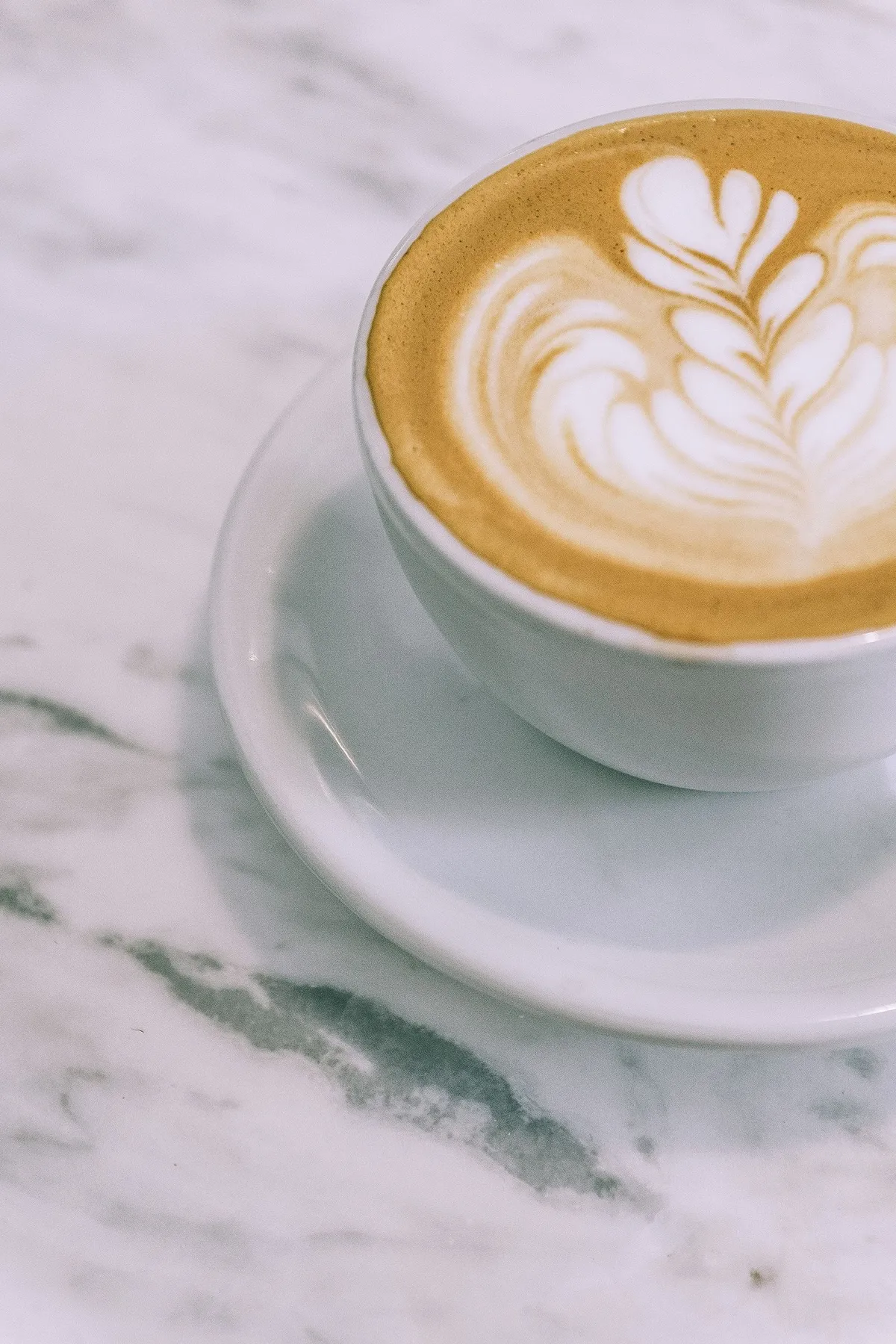 Cappuccino con arte latte sobre una mesa de mármol
