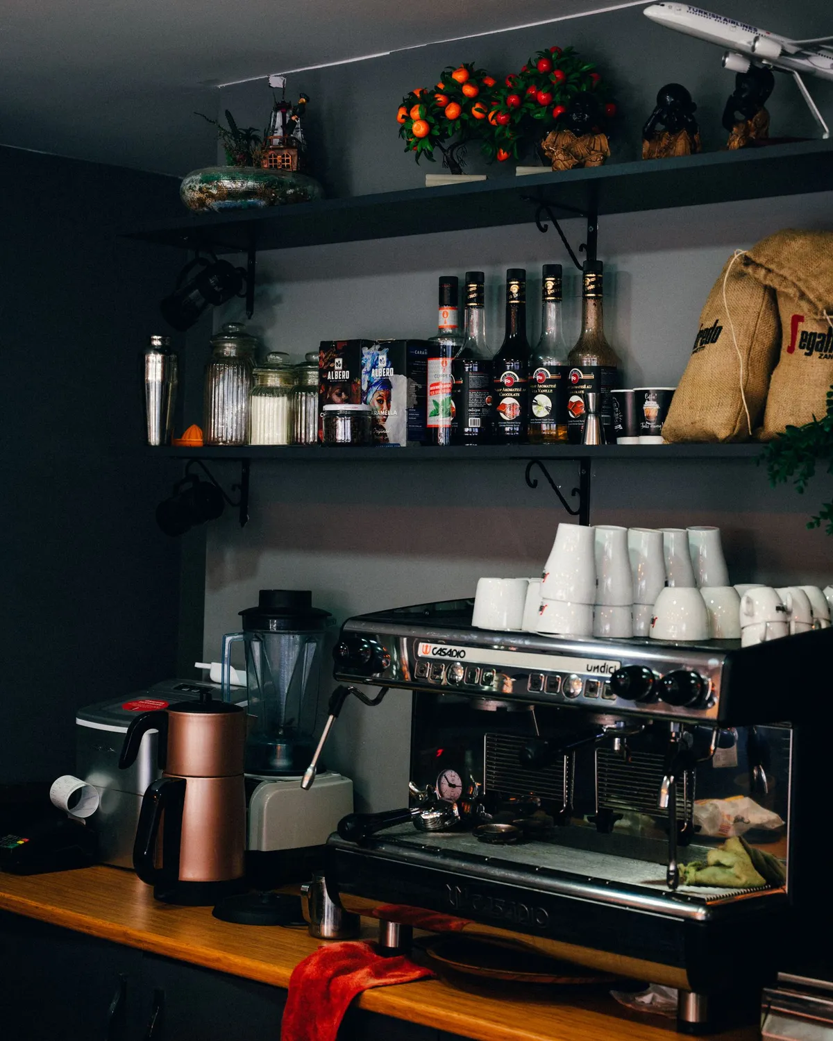 Barra de cafetería española con máquina de espresso, tazas y paquetes de café