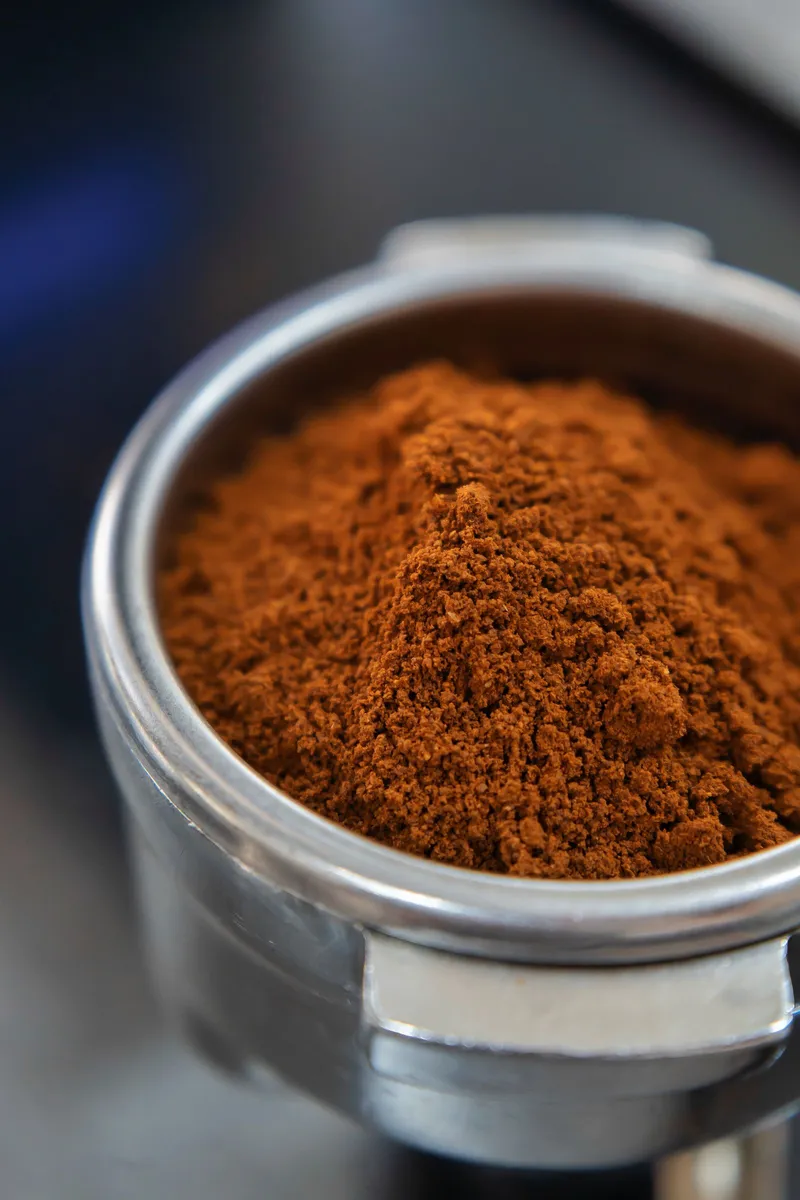 Café molido fino nivelado dentro de un portafiltros metálico
