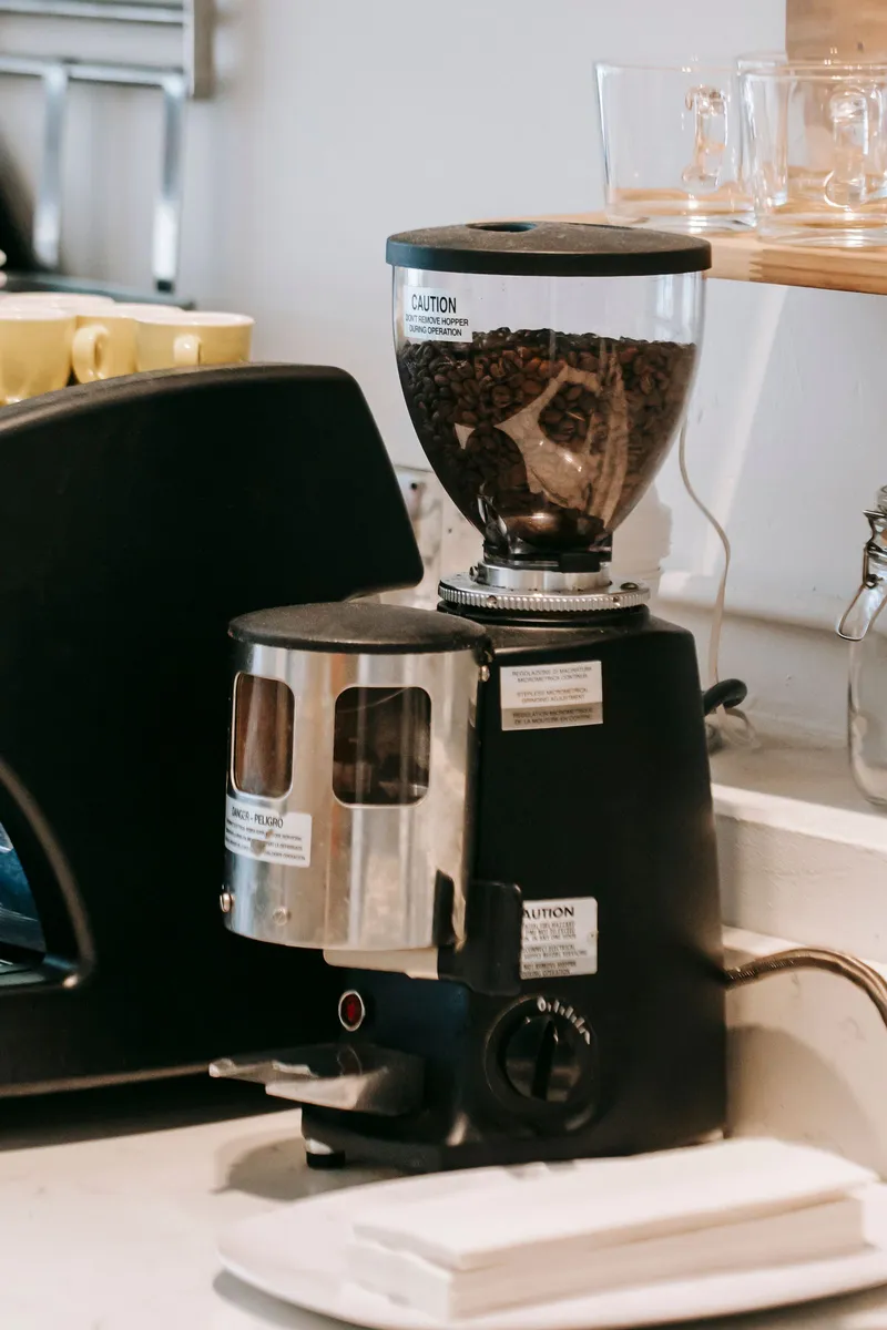 Molinillo de café eléctrico sobre la encimera junto a la cafetera