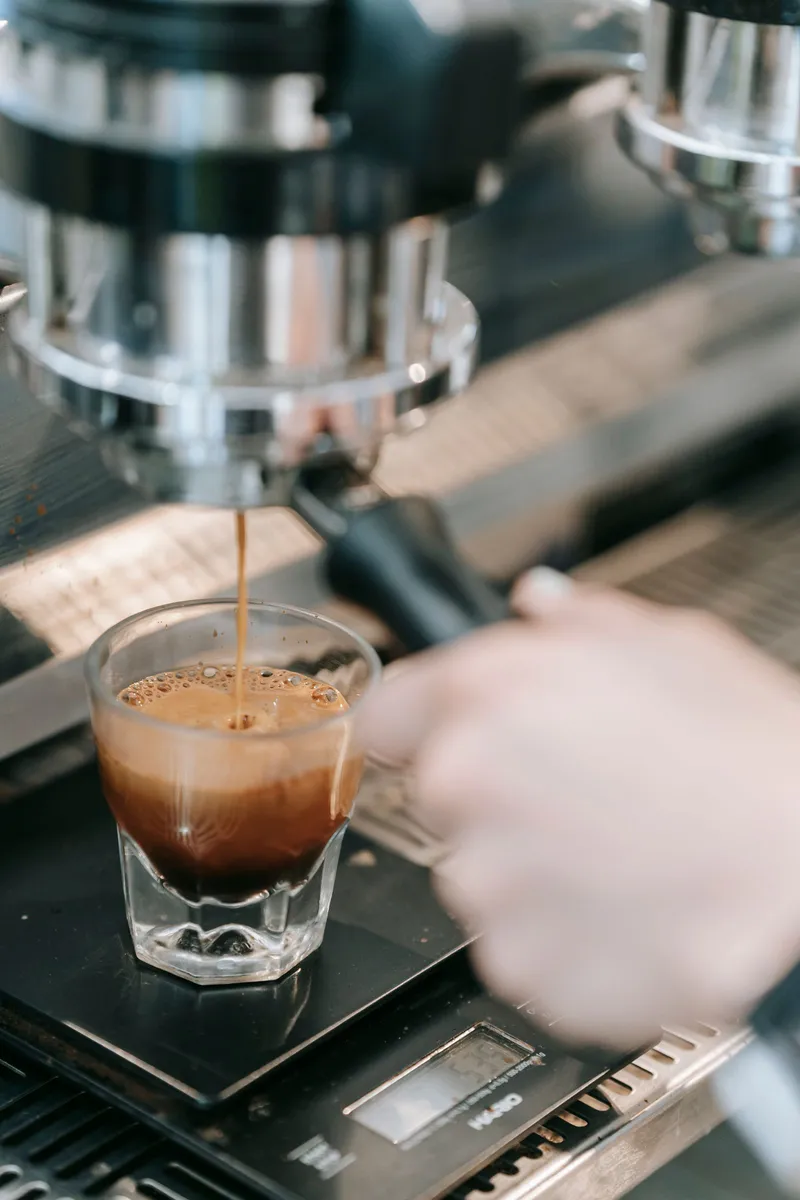 Espresso recién extraído cayendo de la máquina en un vaso